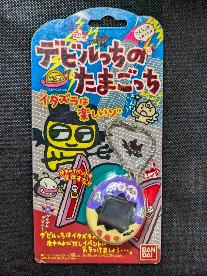 Packaged purple-and-white Tamagotchi toy keychain attached to an illustrated backing card.