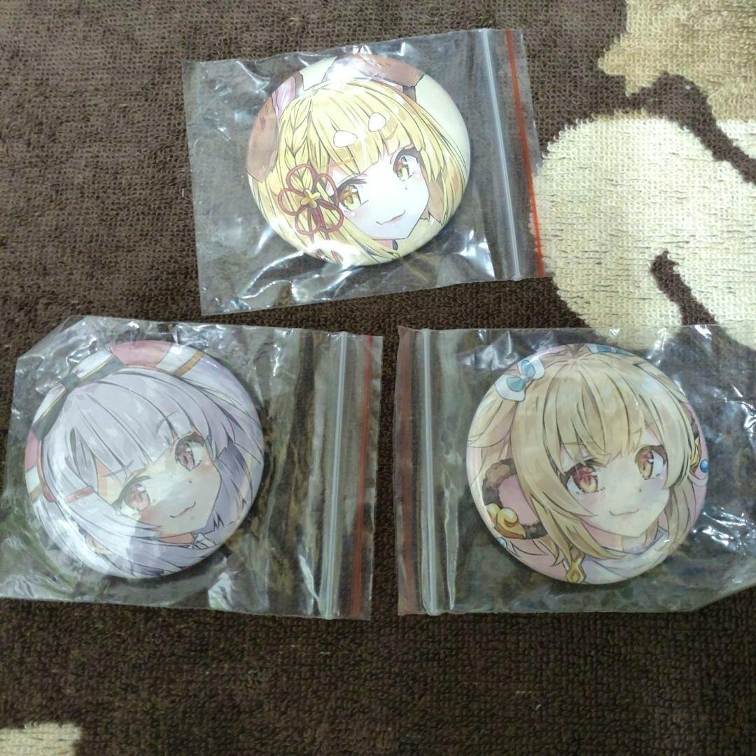Three round can badges featuring illustrated anime character faces, each in a resealable plastic bag on a brown towel.