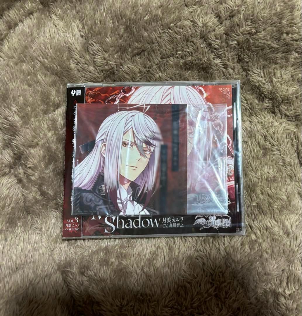Photo of the CD for ディアラバ 月浪カルラ with an illustrated message bromide placed on top, in its plastic wrap on a fuzzy surface.