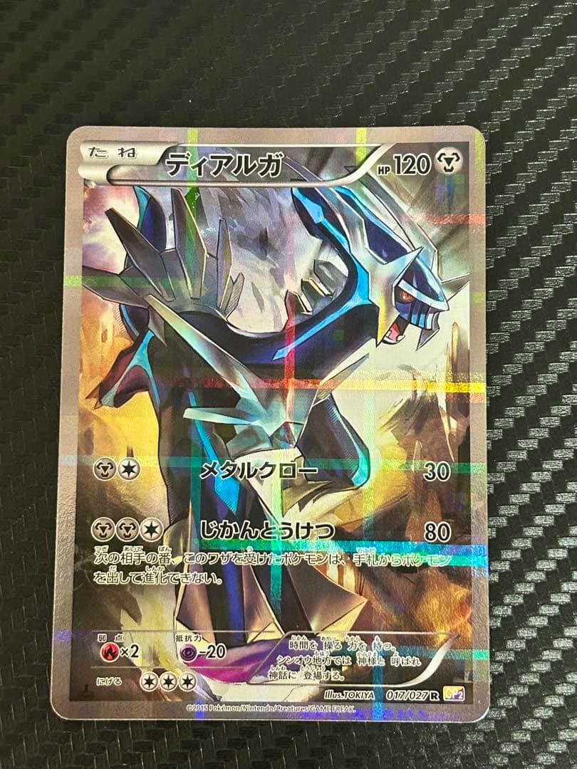 Photo of the holographic Dialga trading card (ディアルガ) showing the full card front on a textured black surface.