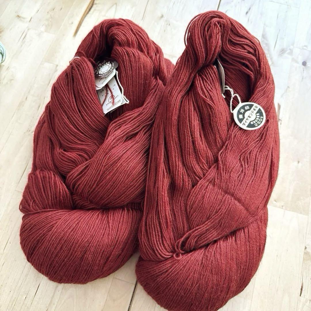 Two skeins of ダイヤモンド毛糸 red wool yarn (color no. 775) laid on a wooden surface.