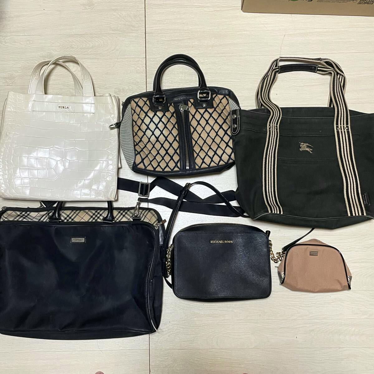 Six women's bags displayed on the floor, including a Burberry canvas tote and other branded handbags.