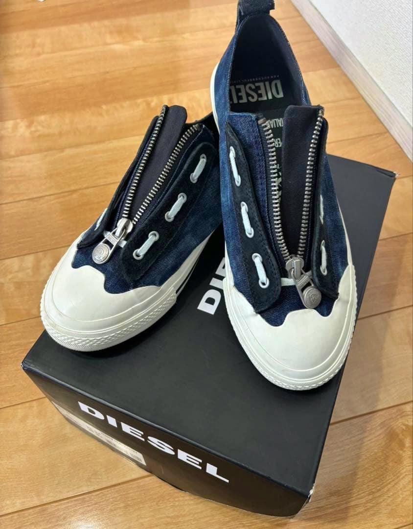 Pair of navy DIESEL sneakers with front zippers displayed on a DIESEL shoebox.