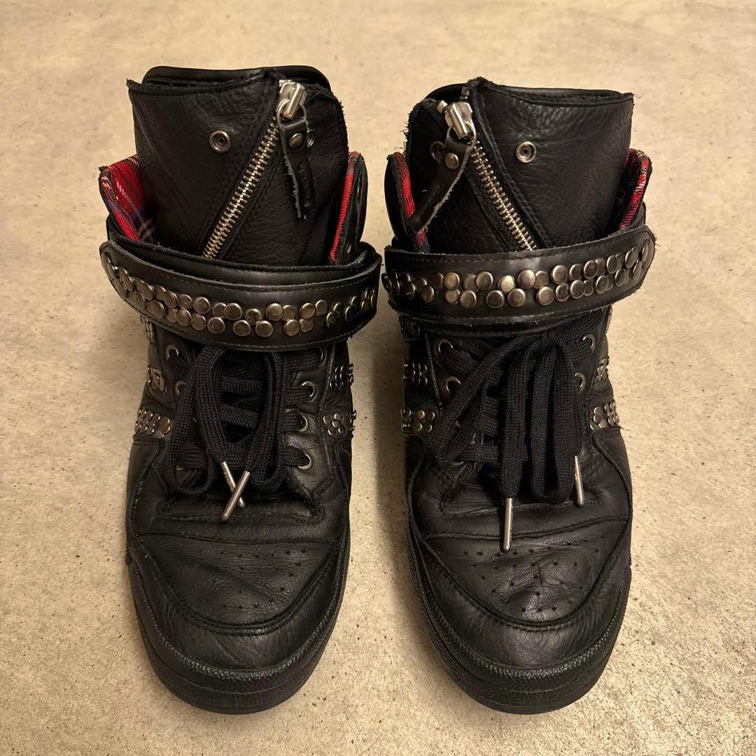 Pair of black DIESEL x adidas leather high-top sneakers with studded ankle straps photographed from above on a beige floor.