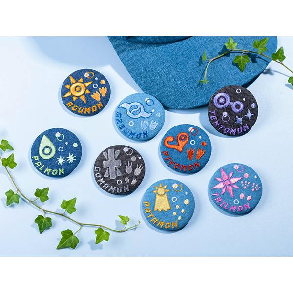 Eight round denim embroidered can badges from the Digimon Adventure series arranged on a light background.