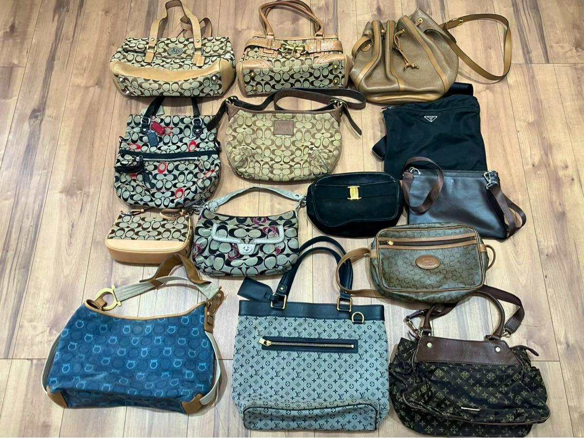 A collection of assorted branded handbags and shoulder bags laid out on a wooden floor.