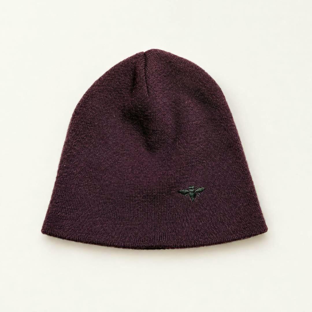 Dior Homme dark burgundy knit beanie with a small bee embroidery laid flat on a light background.