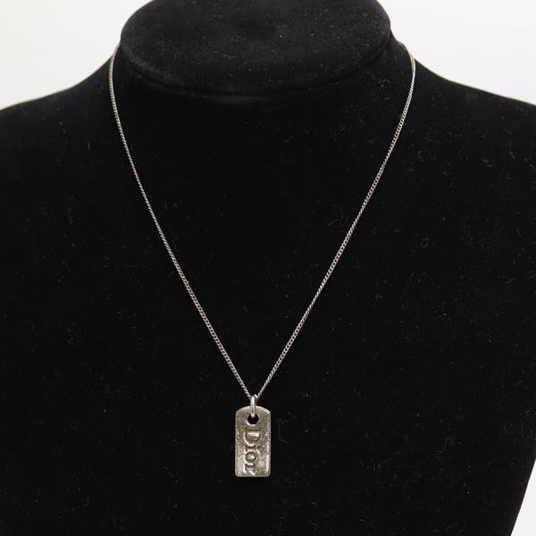 Silver-color Dior necklace with a small rectangular pendant displayed on a black velvet bust.