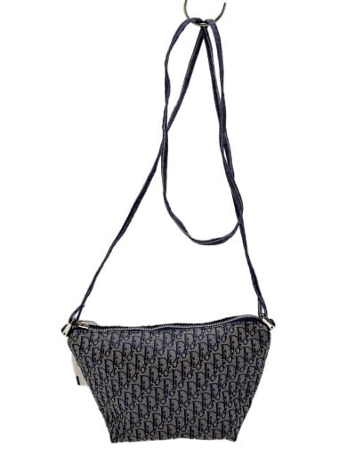 Front view of a grey patterned shoulder bag with a long strap hanging from a hook.