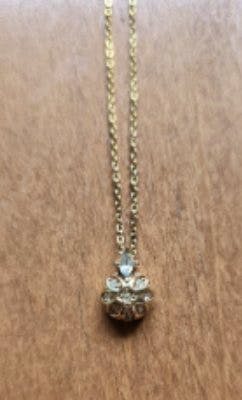 Gold-tone Dior necklace with a cluster stone pendant lying on a wooden surface.