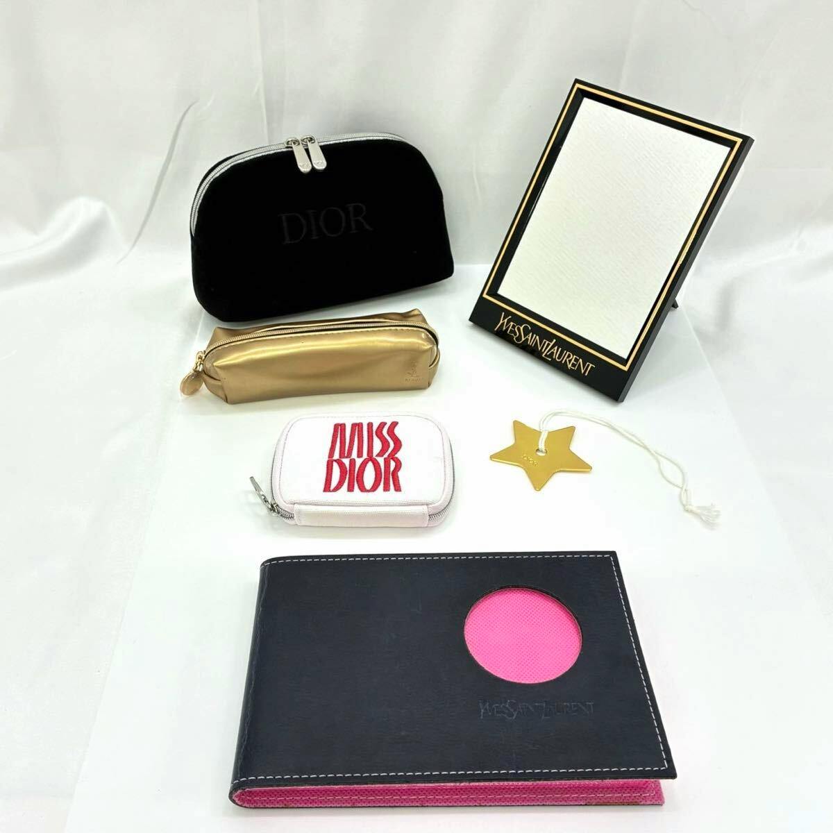 Several novelty brand small items on a white background, including multiple pouches, a Miss Dior zip case, a Yves Saint Laurent framed mirror, and a gold star charm.