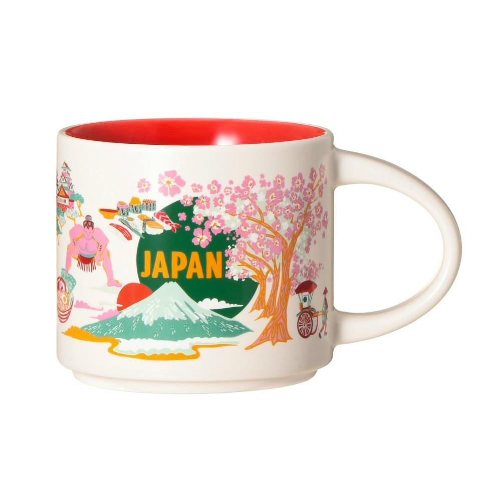 White ceramic mug with Japan-themed illustrations including cherry blossoms, Mount Fuji, and a red interior.