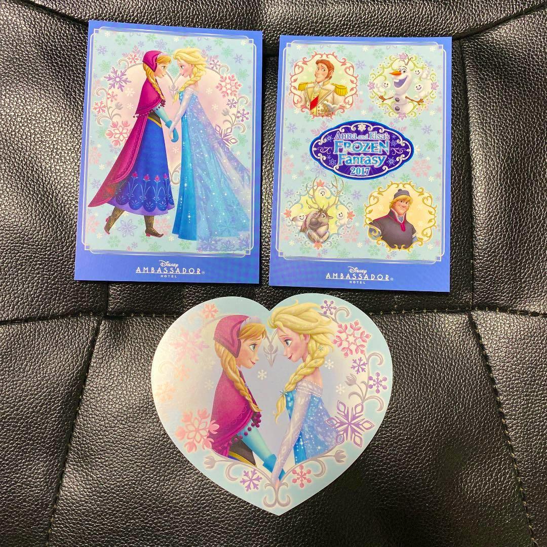 Three Disney Ambassador Hotel postcards featuring Frozen characters Anna and Elsa, two rectangular cards and one heart-shaped card arranged on a black surface.