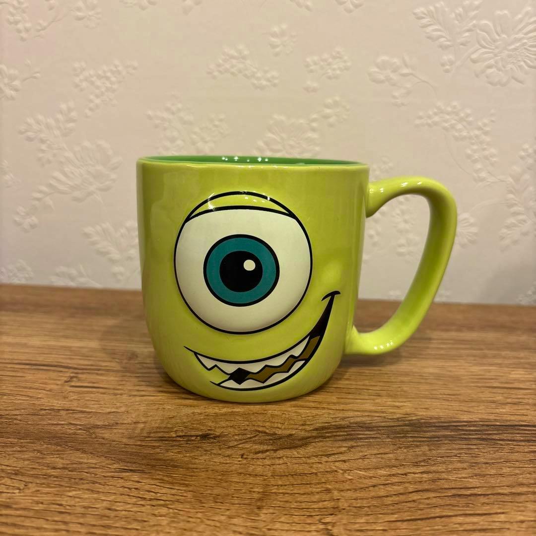 Green ceramic Mike Wazowski mug showing the front with one large eye and a smiling mouth.