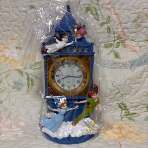 Front view of a Disney Peter Pan Big Ben-style tabletop clock figure with character figures and an analog clock face, wrapped in clear plastic.