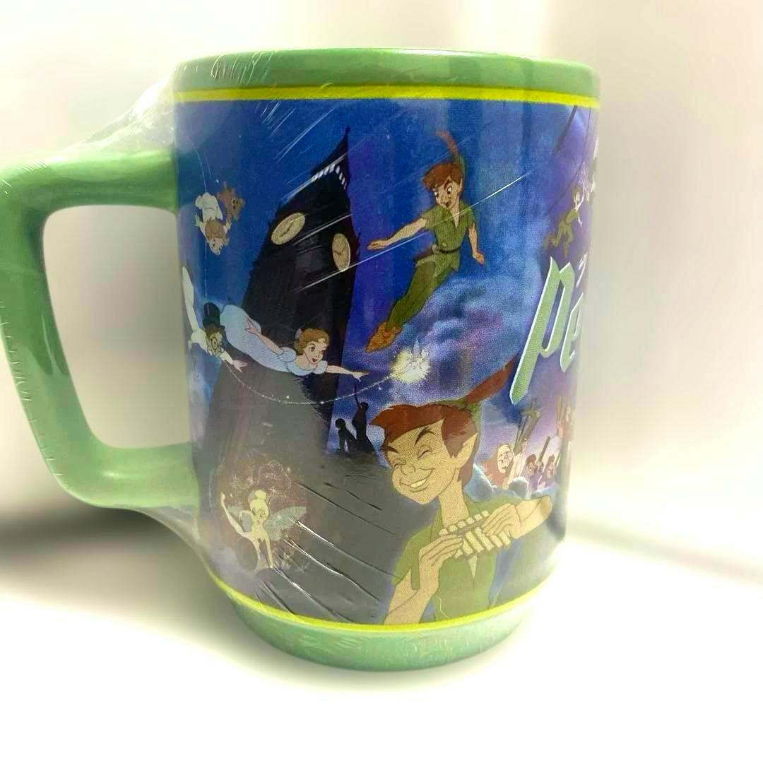 Green ceramic Peter Pan mug showing printed artwork of Peter Pan, Tinker Bell, and other characters flying near Big Ben.