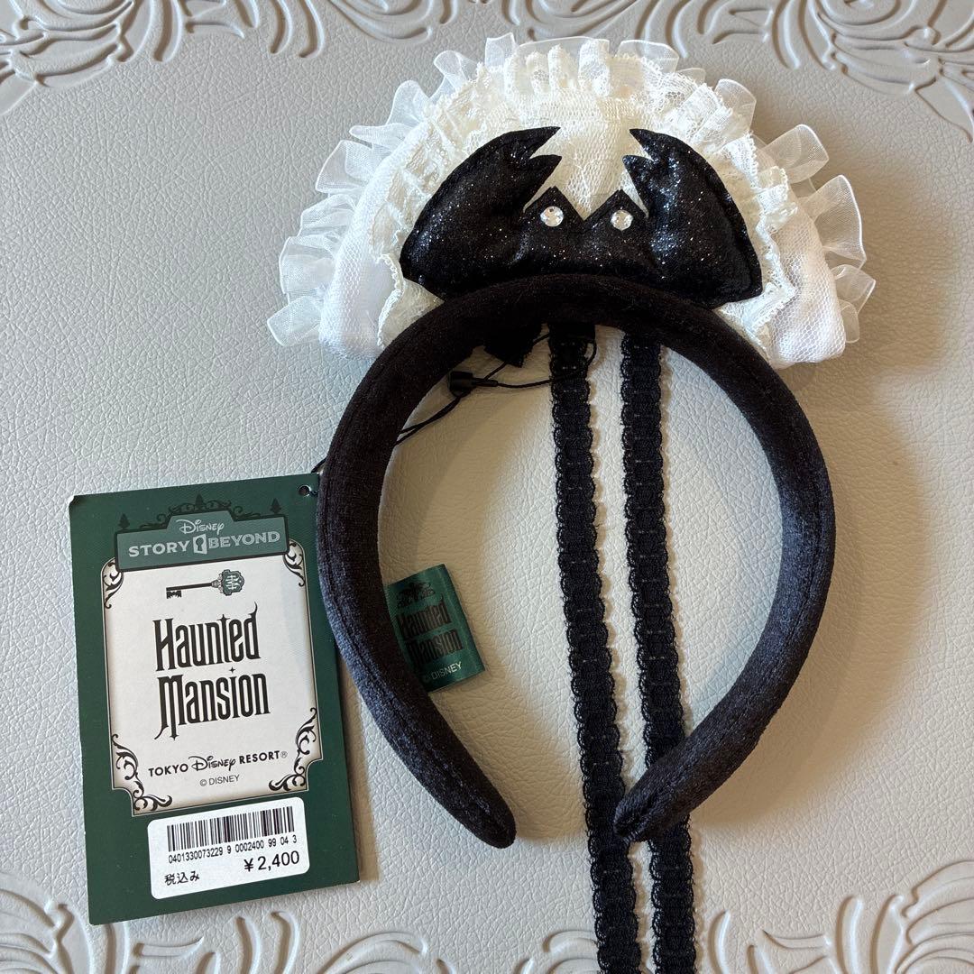 Front view of the Disney Haunted Mansion headband showing a white lace ruffle, black band, and attached tag.