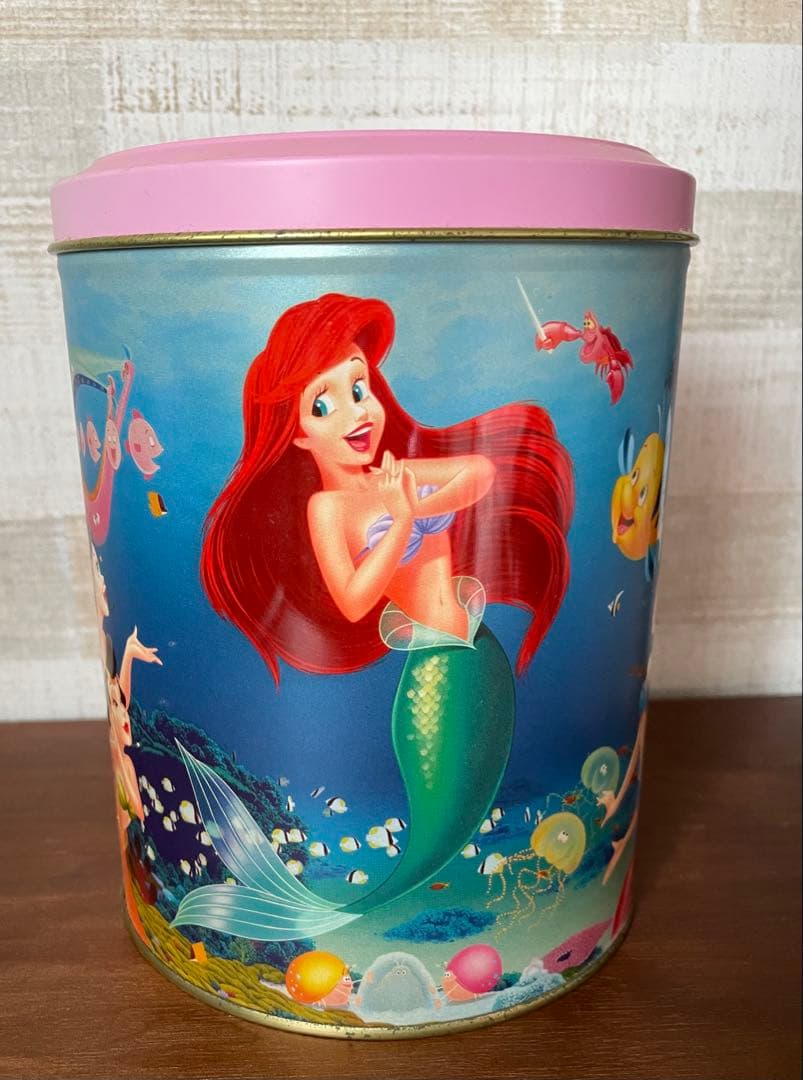 Round tin box with a pink lid featuring Ariel from The Little Mermaid on the front.