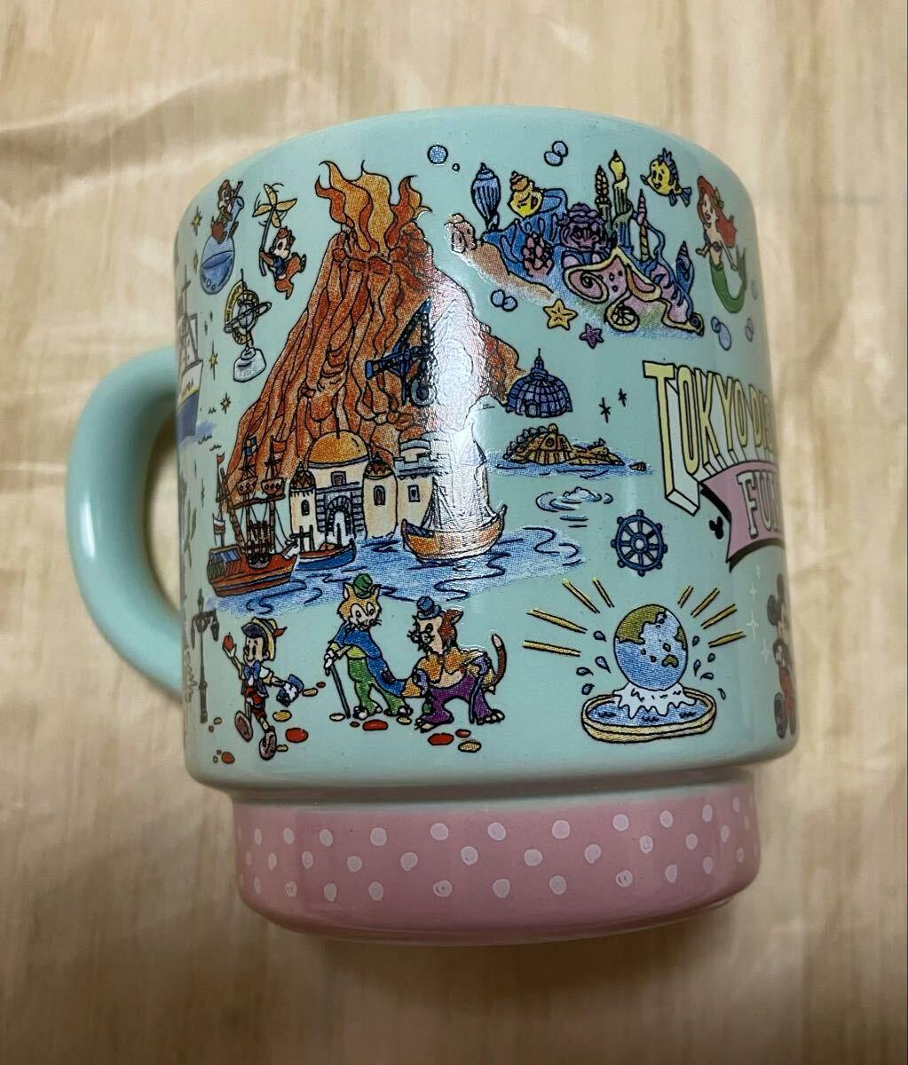 Side view of a light-blue ceramic mug with Tokyo DisneySea-themed illustrations and a pink polka-dot base, showing the handle.