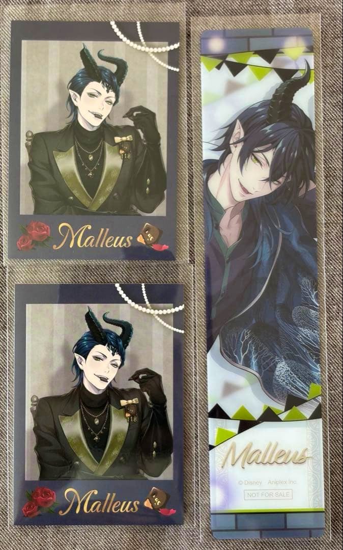 A clear plastic bookmark and two rectangular character cards featuring Malleus displayed on a fabric background.