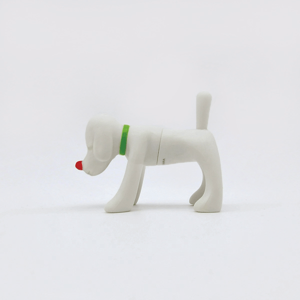 Side view of a white dog fridge magnet with a green collar and a red nose on a white background.