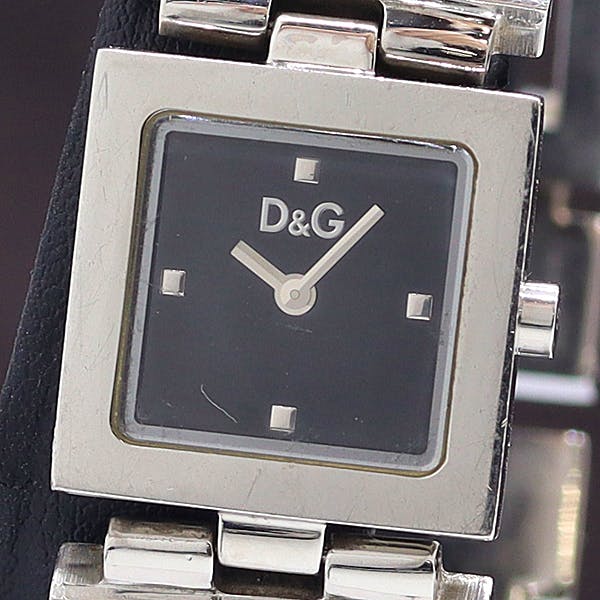 Close-up of the Dolce & Gabbana men's wristwatch with a black square dial showing the D&G logo and a metal bracelet.