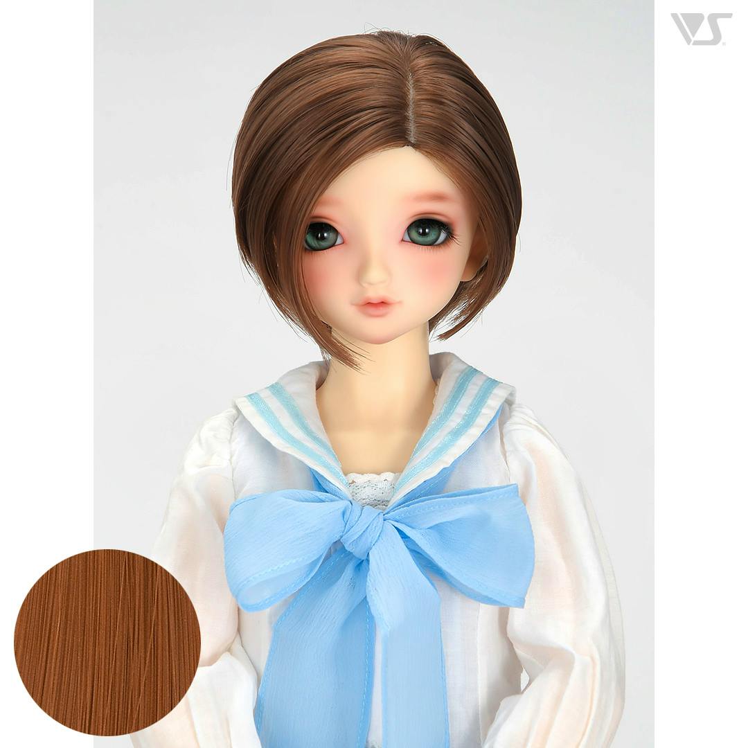 Front view of a doll wearing a white sailor-style blouse with a large light-blue bow, shown with short cork-brown hair.