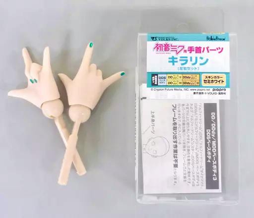 Two semi-white DD wrist/hand parts with green-painted nails alongside the clear plastic packaging and Japanese product label.