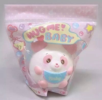 Pink-and-white panda plush mascot shown inside clear retail packaging with a 'HUG ME! BABY' header.