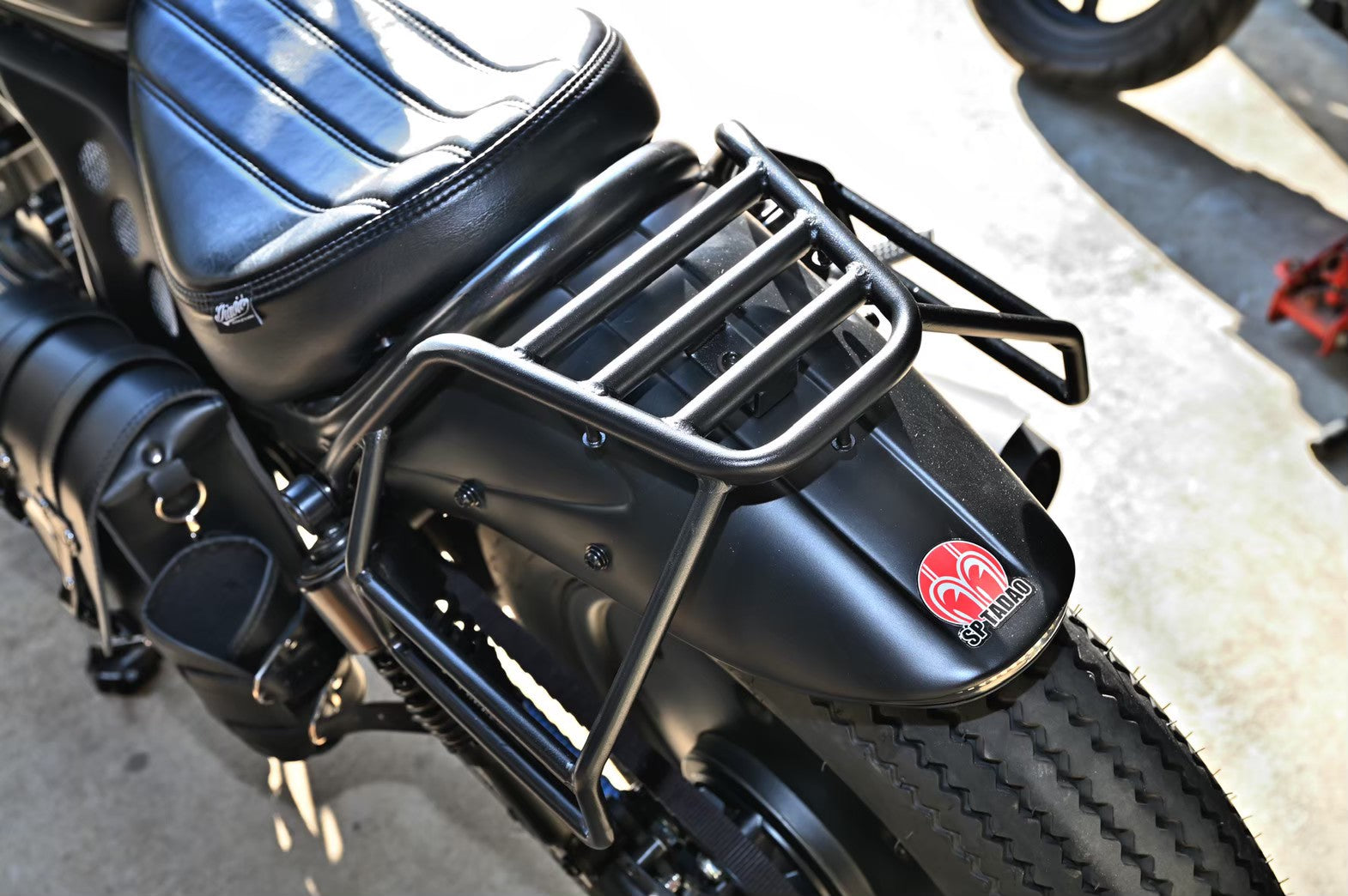 Black metal rear carrier rack mounted on a motorcycle short rear fender next to the seat.