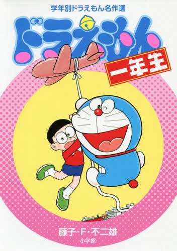 Front cover of the children's picture book showing Doraemon holding a hat while a schoolboy character hangs from its string, with Japanese title text and a pink polka-dot background.