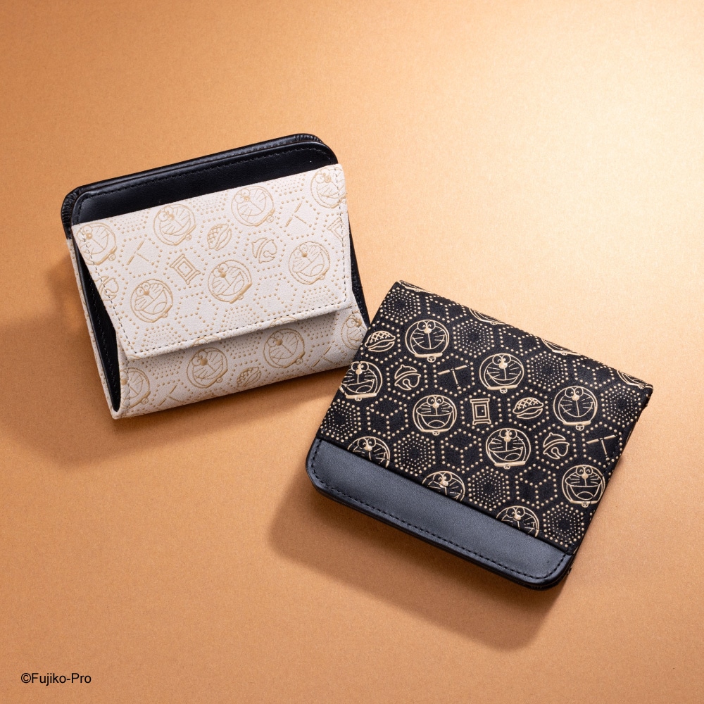 Two mini cow-leather wallets with Doraemon-patterned Koshu Inden, one white and one black, displayed on a beige background.