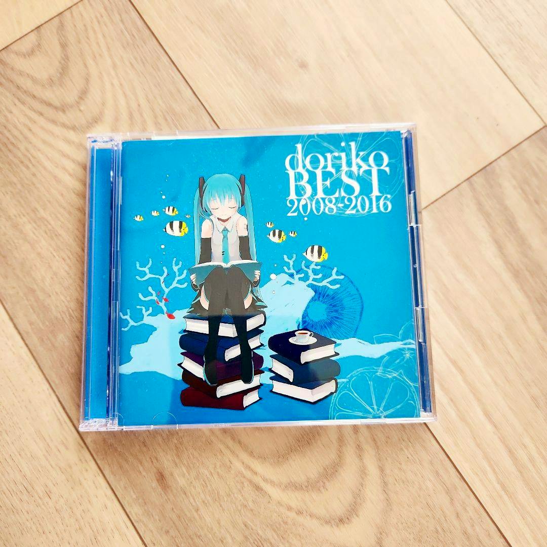 Front of the CD case for doriko BEST 2008-2016 showing blue cover art with an illustrated girl sitting on stacked books.