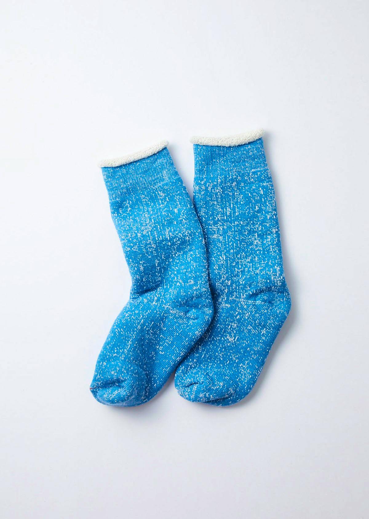 A pair of blue double-face crew socks laid flat on a white background, showing a speckled knit and white cuffs.