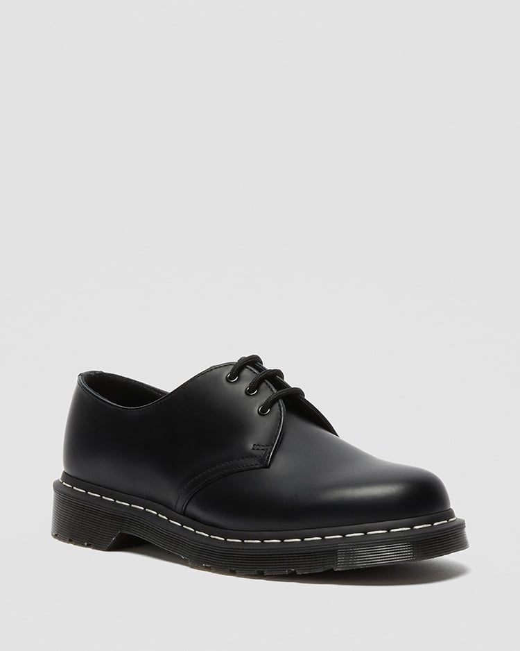 Black leather 3‑hole shoe with white welt stitching shown at a three-quarter angle on a light gray background.