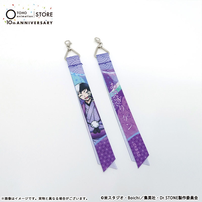 Photograph of two purple fabric ribbon keychains featuring Asagiri Gen artwork and metal lobster-clasp attachments on a white background.