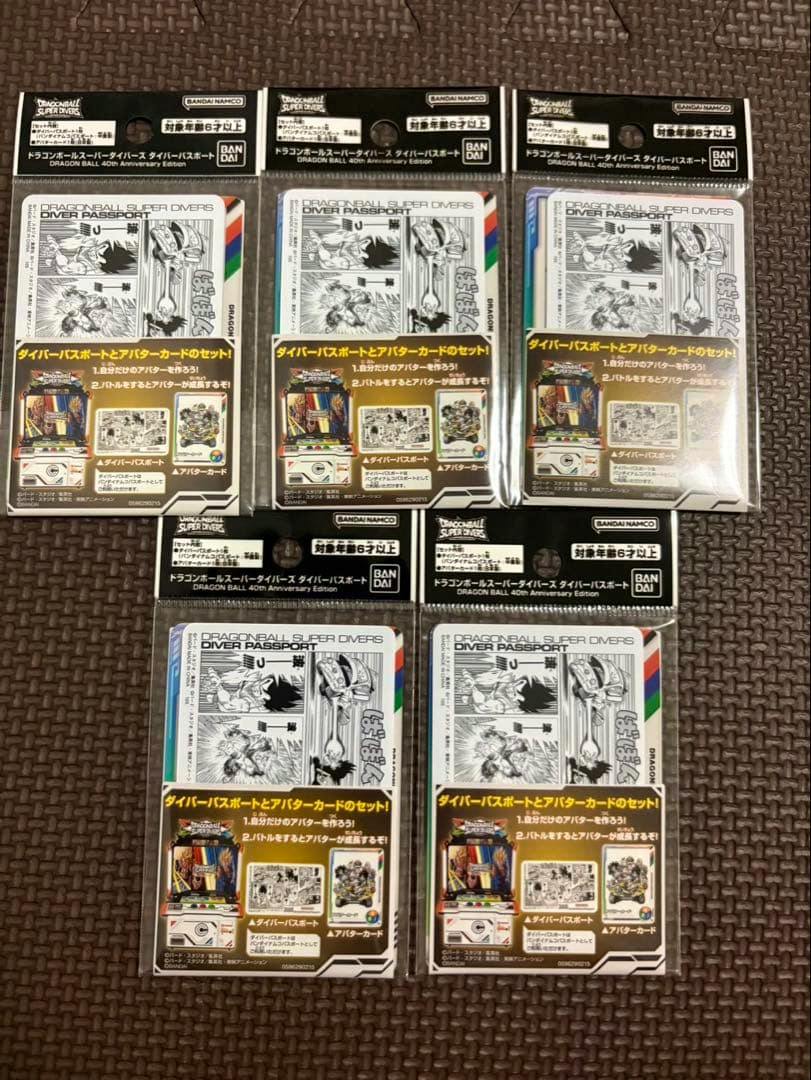 Five sealed Dragon Ball Super Divers 40th Anniversary diver passport packs (5 pieces) displayed on a brown textured surface.