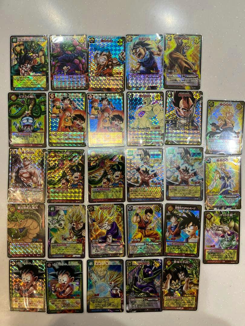 Photo of multiple Dragon Ball trading cards with holographic foil arranged in a grid on a white surface.