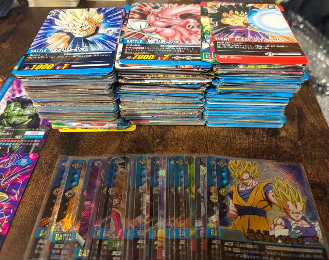 Stacks of Dragon Ball Data Carddass trading cards on a wooden surface with several holographic cards fanned out in front.