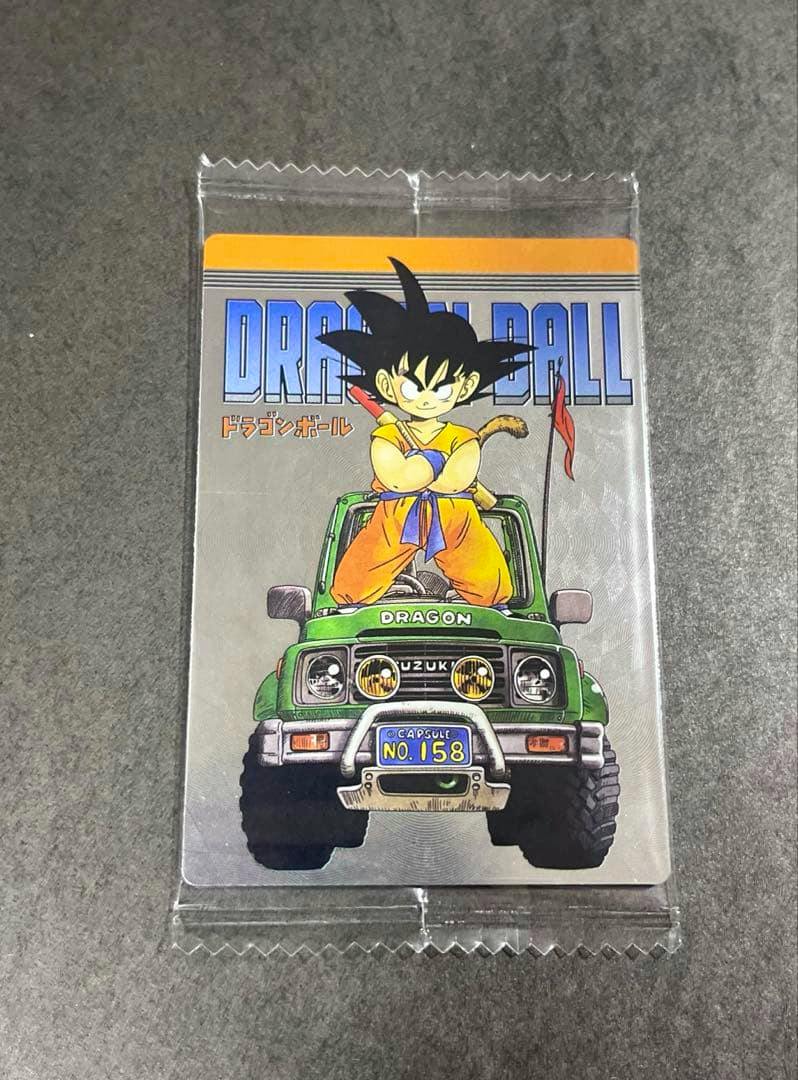 Sealed Dragon Ball card showing young Son Goku standing on a green vehicle with the DRAGON BALL title at the top.