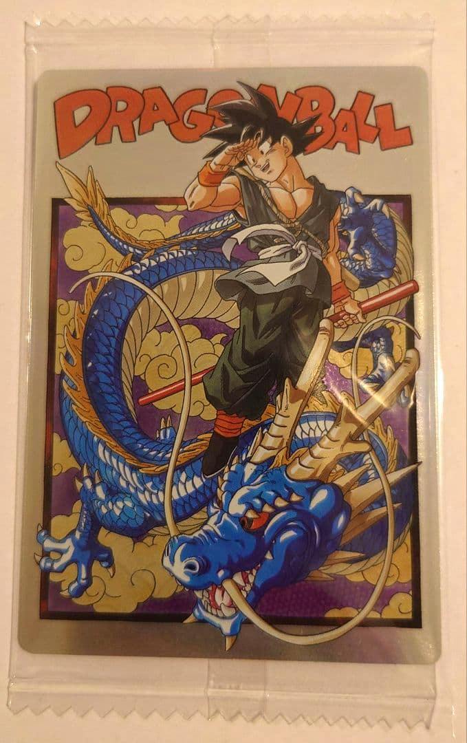 Front of a Dragon Ball trading card showing Son Goku standing with a blue Shenron dragon, photographed inside a clear plastic sleeve.