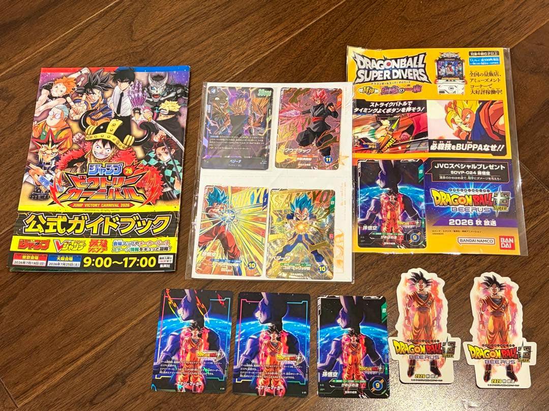Multiple Dragon Ball Super Diverus trading cards, character stickers, and an official guide book arranged on a wooden surface.