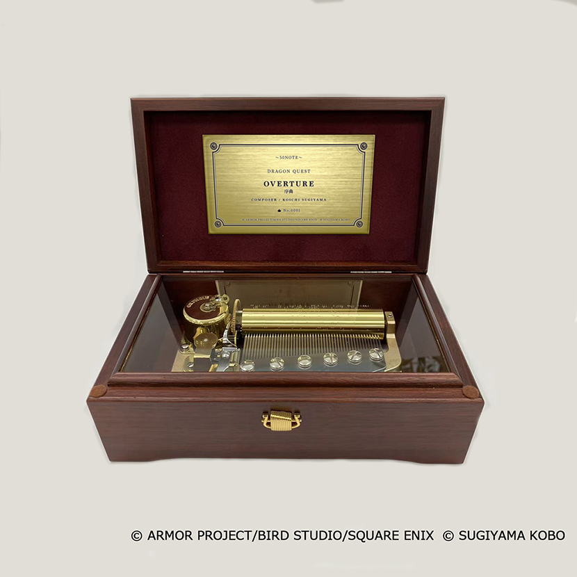Open wooden music box showing the brass 50-note movement and an interior plaque.