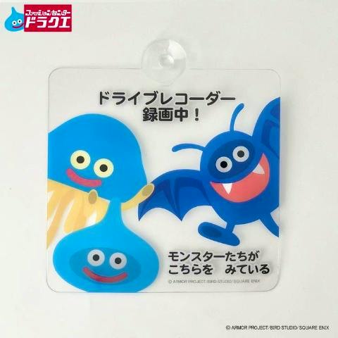 Square plastic car sign showing Dragon Quest slime and bat characters with Japanese text and a suction cup.