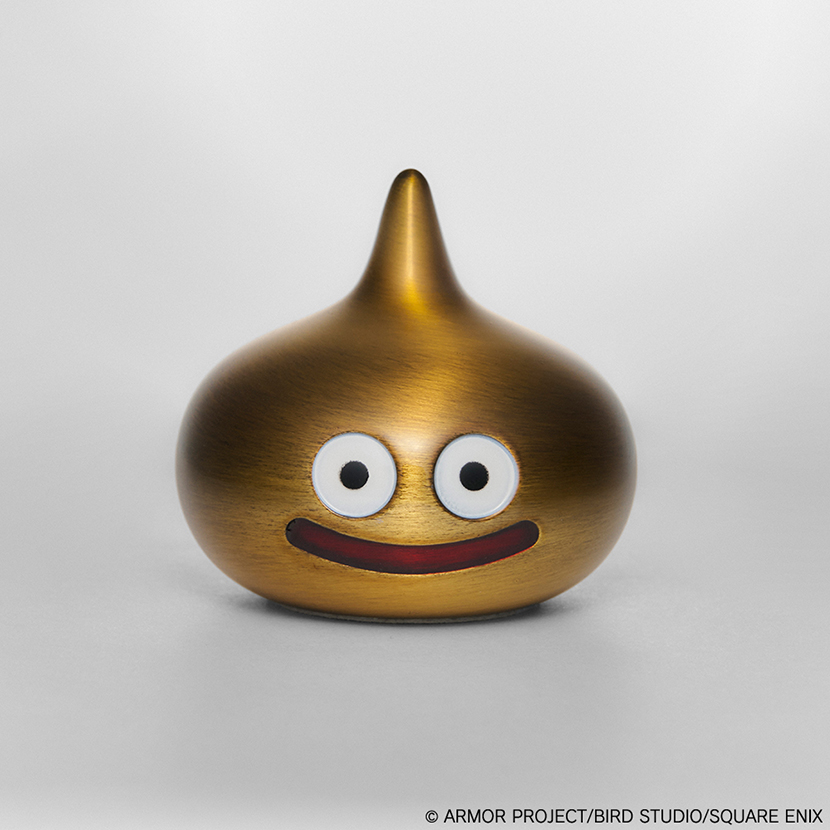 Metallic gold Dragon Quest Slime figure with painted eyes and a smiling mouth on a neutral background.