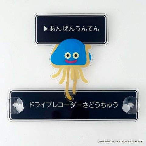 A Dragon Quest car sign showing a jellyfish-like character between two rectangular black message plates with suction cups.