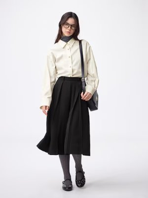 Model wearing black drape culottes paired with a cream blouse and shoulder bag.