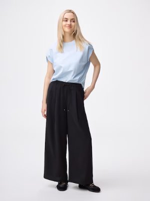 Model wearing the drape wide pants in black with a light blue top on a white background.