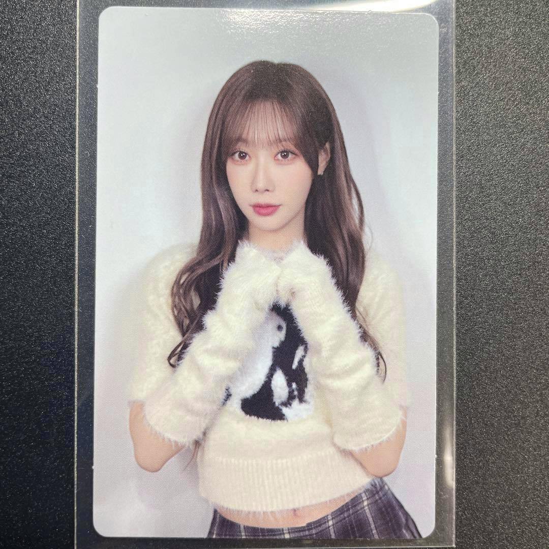 Photocard showing a portrait of a woman wearing a white fuzzy sweater and matching gloves, photographed inside a clear plastic sleeve.