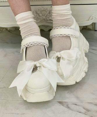 White Dreamy Series platform 2-way sneakers with large decorative bows shown worn on feet with socks.